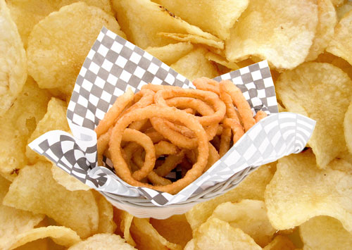 A basket of onion rings on top of some potato chips.