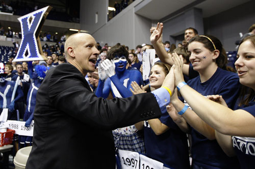 Man in a suit giving high fives to sports fans.