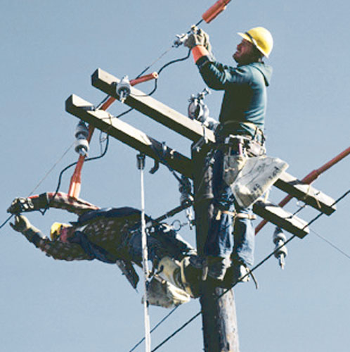 Two men attached to a telephone pole working on a powerline.