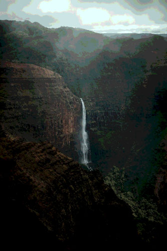 A water fall on top of a cliff with a fogy overhang.